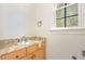 Powder room featuring a granite countertop, wooden cabinet, and a window at 15 Treviso Pl, Durham, NC 27707