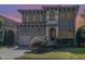 Twilight view of a two-story stucco home with arched windows, beautiful landscaping, and a two-car garage at 15 Treviso Pl, Durham, NC 27707