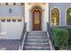 Elegant front entryway showcasing a decorative wood door, stone steps, and manicured landscaping at 15 Treviso Pl, Durham, NC 27707