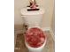 Close-up of a standard white toilet with a plush, round cover on beige tile flooring at 1633 Snow Mass Way, Durham, NC 27713