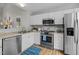 Kitchen with stainless steel appliances, light countertops, white cabinets, and wood-look flooring at 205 Town Creek Dr, Cary, NC 27519