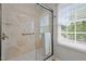 Bright bathroom shower with stone textured shower panels, glass door, and natural light from the window at 205 Town Creek Dr, Cary, NC 27519