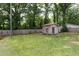 Spacious backyard with a wooden shed, lush green grass, and a secure wooden fence at 212 E Rockway St, Durham, NC 27704