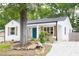 Quaint white cottage with stone foundation, shutters, blue front door, and rock-lined flowerbeds at 212 E Rockway St, Durham, NC 27704