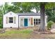 Charming white cottage with blue door, stone accents, wood shutters, and welcoming front porch at 212 E Rockway St, Durham, NC 27704