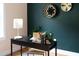 An office with a desk decorated with plants and books in front of a green accent wall and stylish decor at 212 E Rockway St, Durham, NC 27704