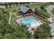 Aerial view of a large community pool with colorful umbrellas, lounge chairs, and a modern clubhouse in the background at 224 Daniel Ridge Rd, Wendell, NC 27591