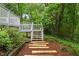 View of a backyard featuring garden landscaping and wooden stepping stones leading up to a cozy deck at 2324 Stevens Rd, Raleigh, NC 27610