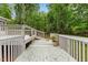 Image showcases a large deck with painted flooring and white railings, surrounded by lush greenery and trees at 2324 Stevens Rd, Raleigh, NC 27610