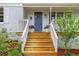 Inviting front porch with freshly stained stairs, flower pots, and blue front door at 2324 Stevens Rd, Raleigh, NC 27610