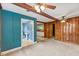 A cozy living room with wood walls, ceiling fans, and access to other rooms at 2324 Stevens Rd, Raleigh, NC 27610
