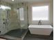 New bathroom featuring glass shower, freestanding tub, and modern fixtures in a well-lit space at 2577 Silas Peak Ln, Apex, NC 27523