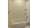 A bright and clean bathroom featuring tiled walls, a shower-tub combo, and storage shelving at 2577 Silas Peak Ln, Apex, NC 27523