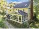 Rear exterior view showcasing the sunroom with many windows, stone pathway, and the house's yellow siding at 2645 Ridgewell Ct, Raleigh, NC 27613