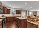 Gourmet kitchen with dark wood cabinets, granite countertops, and stainless steel appliances flows into the dining and living areas at 3413 Fairstone Rd, Wake Forest, NC 27587