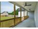 Inviting covered back porch with wooden railings and ceiling fans, overlooking a lush backyard and neighboring homes at 3417 Aspen Rd, Rocky Mount, NC 27804