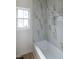 Bright bathroom featuring tub with marble-look tile surround and a large window at 3417 Aspen Rd, Rocky Mount, NC 27804