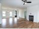 Bright living room featuring hardwood floors, a ceiling fan, large windows, and a fireplace with a white mantle at 3417 Aspen Rd, Rocky Mount, NC 27804