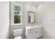 Bathroom with vanity, white cabinets, stone countertops, decorative mirror, and natural light at 4109 City Of Oaks Wynd, Raleigh, NC 27612