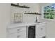 Wet bar with white cabinets, undermount beverage cooler, and floating shelves at 4504 Ryegate Dr, Raleigh, NC 27604