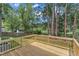 New wooden deck overlooking a spacious backyard, lush trees, and a peaceful pond on a sunny day at 4504 Ryegate Dr, Raleigh, NC 27604