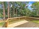 A view of a wood deck overlooking a large backyard that slopes to a pond and lush trees at 4504 Ryegate Dr, Raleigh, NC 27604