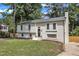 Beautiful two-story white brick home with a lush green lawn, mature trees, and a chimney at 4504 Ryegate Dr, Raleigh, NC 27604