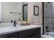 Bathroom featuring a granite countertop, dark cabinets, framed mirror, and a shower with gray tiling at 515 N Churton St # Ste 201, Hillsborough, NC 27278