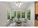 Bright dining room with glass table, modern chandelier, and large windows overlooking a wooded view at 5315 Fortunes Ridge Dr, Durham, NC 27713