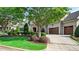 Serene home exterior with lush greenery, manicured lawn, stone accents, and a spacious driveway leading to the attached garage at 603 Hawks Ridge Ct, Apex, NC 27539