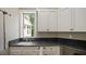 Functional laundry room with a sink, dark countertops, white cabinets, and an exterior view at 603 Hawks Ridge Ct, Apex, NC 27539