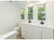 Bathroom with double sink vanity, white cabinets, laminate flooring, and lots of natural light at 612 Dunbar St, Durham, NC 27701