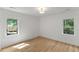 Inviting bedroom filled with natural light has wood flooring, white walls, and dual windows at 6709 Sunhaven Pl, Raleigh, NC 27615