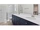 Bathroom with dual sinks, white countertops, blue vanity cabinets, a glass-enclosed shower, and wood-look floors at 679 Jasmine Rd, Fuquay Varina, NC 27526