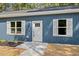 Close-up of a blue home's entrance with white shutters, a charming doorway, and a manicured lawn at 679 Jasmine Rd, Fuquay Varina, NC 27526
