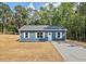 Charming blue one-story home featuring white trim and shutters, nestled in a wooded area at 679 Jasmine Rd, Fuquay Varina, NC 27526