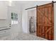 Kitchen area with a rustic barn door, white cabinetry, granite countertops, and stainless-steel appliances at 679 Jasmine Rd, Fuquay Varina, NC 27526