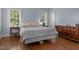 Bedroom with hardwood floors, side tables, a dresser, and two windows at 70 S Patterson St, Coats, NC 27521