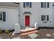 Bright red front door with brick steps and decorative accents, set in a white-painted brick facade at 70 S Patterson St, Coats, NC 27521