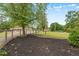 Mulched flower bed next to a fenced yard with lawn and outbuildings in the distance at 70 S Patterson St, Coats, NC 27521