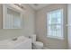 Bathroom featuring a sink with a mirror, toilet, and window providing natural light, creating a clean and functional space at 7024 Beaverwood Dr, Raleigh, NC 27616