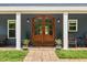 Close-up of front doorway with stately wooden doors, decorative plants and stylish lighting, adding to the home's character at 741 Sinai Cir, Hillsborough, NC 27278