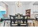 Dining room with black wood table, six cushioned chairs, modern light fixture, wood floors, and a glass door at 81 Paperwhite Pl # 213, Clayton, NC 27527