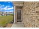 View of the front door and brick exterior, with a glimpse of the inviting neighborhood in the background at 81 Paperwhite Pl # 213, Clayton, NC 27527