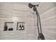 A closeup of the tiled shower featuring shampoo niches and a black showerhead at 81 Paperwhite Pl # 213, Clayton, NC 27527