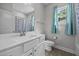 Bright bathroom with a white vanity, shower with blue curtain and blue window curtains at 834 Mamie Upchurch Rd, Lillington, NC 27546
