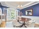 Elegant dining room with a blue accent wall, large windows with shutters, and a modern chandelier at 8605 Stanton Pl, Raleigh, NC 27615