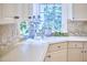 Close-up of kitchen sink with decorative plants and neutral tile backsplash, complemented by white cabinetry at 8605 Stanton Pl, Raleigh, NC 27615