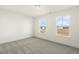 An empty, carpeted bedroom featuring white walls, baseboards, and two windows bringing in natural light at 87 Browning Mill Dr, Wendell, NC 27591