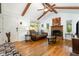 Inviting living room featuring hardwood floors, exposed wooden beams, a brick fireplace, and large windows at 8812 Valley Hill Ct, Apex, NC 27539